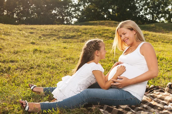 Happy little girl hugging her mother's pregnant belly — Stock Photo, Image