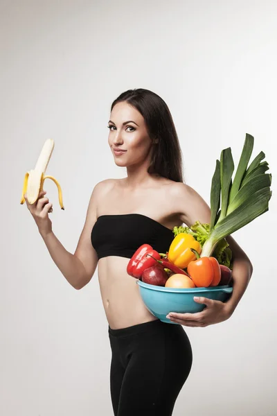 Portret młodej kobiety pasuje trzymając owoce i warzywa — Zdjęcie stockowe