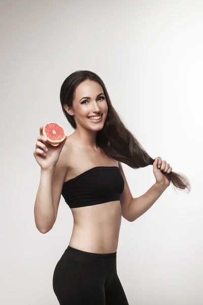 Retrato de mujer joven en forma sosteniendo toronja rosa — Foto de Stock