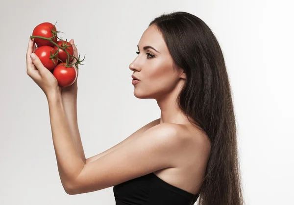 Портрет молодой женщины с глянцевыми красными помидорами — стоковое фото