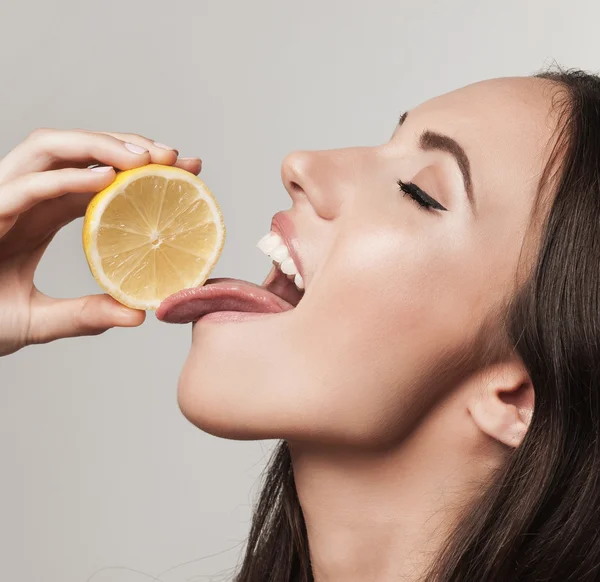 Крупный план портрета молодой женщины, поедающей лимон — стоковое фото