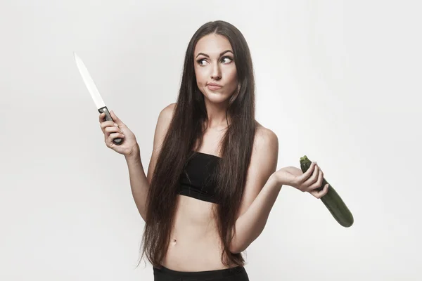 Забавный образ молодой женщины с цуккини и ножом — стоковое фото