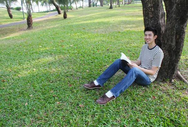 公園で本を読んでいる若い男の人 — ストック写真