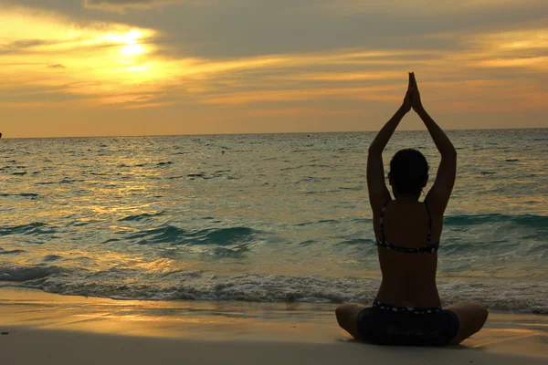 Frau Silhouette praktiziert Yoga am Strand — Stockfoto