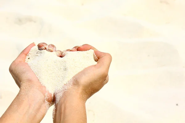 Closeup hands holding white sand heart shape — Stock Photo, Image