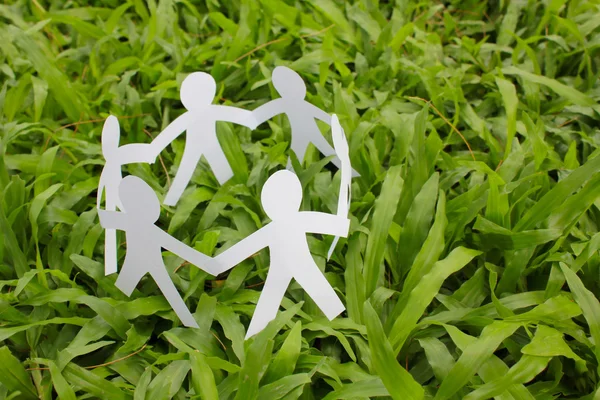 Paper people in a circle with green grass background — Stock Photo, Image