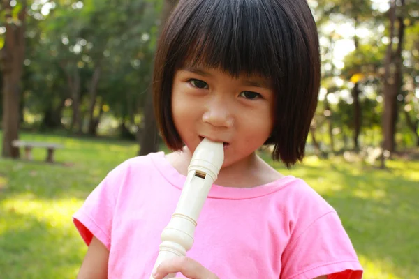 Giovane ragazza che suona il flauto nel parco — Foto Stock