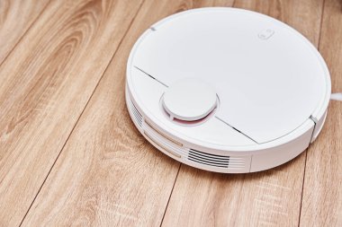Robot elektrik süpürgesi lamine zeminde çalışıyor. Uzaktan kumandalı teknoloji evi