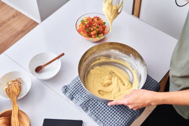 Mutfakta pasta pişiren bir kadın. Eller hamuru karıştırıcıyla dövdü.