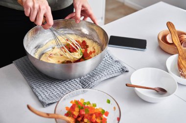 Mutfakta pasta pişiren bir kadın. Eller hamuru karıştırıcıyla dövdü.