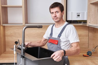 Erkek tesisatçı mutfağa lavabo yerleştiriyor.