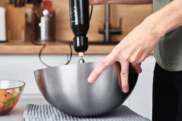 Woman in the kitchen cooking a cake. Hands beat the dough with an electric mixer