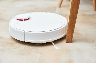 Robot elektrik süpürgesi yerde mobilyalarla çalışıyor. Robot elektrik süpürgesi için engeller var. Modern akıllı ev