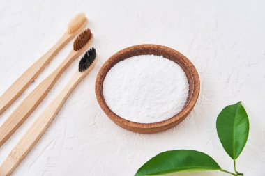 Beyaz arka planda üç ahşap bambu diş fırçası ve kabartma tozu, üst manzara. Çevre dostu diş fırçaları, sıfır atık kavramı