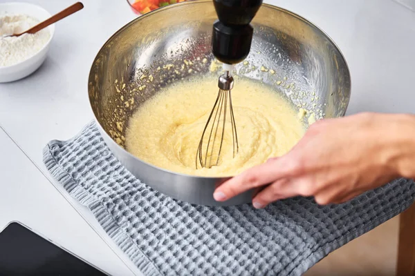 Woman in the kitchen cooking a cake. Hands beat the dough with an electric mixer