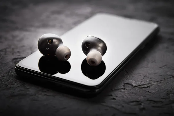 Wireless earphones on a smartphone. Bluetooth headphones for listen audio
