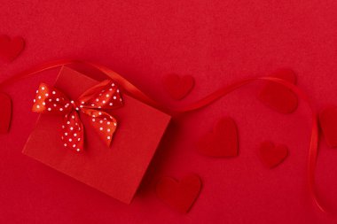 Sevgililer Günü geçmişi. Kırmızı arka planda kalpler ve şenlik kurdelesi olan hediye kutusu. Sevgililer Günü konsepti. Üst manzara, düz uzanma