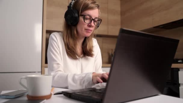 Mujer Trabaja Remotamente Lugar Trabajo Cocina Mujer Con Auriculares Hace — Vídeos de Stock