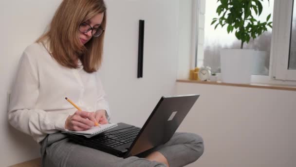 Fernbedienung Frau Macht Notizen Notizbuch Und Druckt Auf Laptop Tastatur — Stockvideo