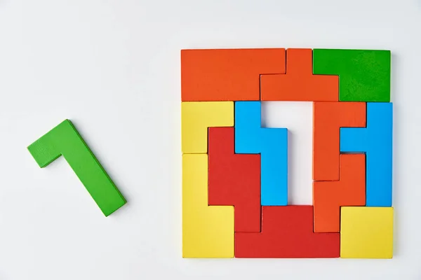 Logical thinking and finishing task concept. Different shapes colorful wooden blocks on a white background