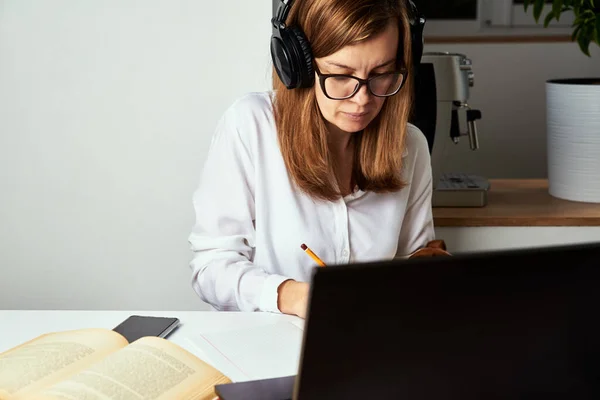 Remote work. Online course, distance education and e-learning concept. Woman in headphones listen audio course at laptop