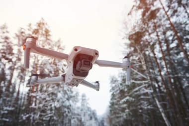 Kış ormanında uçan kameralı bir drone kuadkopteri.
