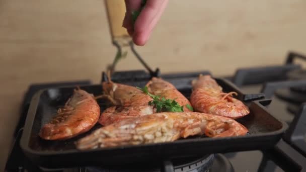 Шеф-кухар збризкає петрушку на грилі великими креветками на сковороді — стокове відео