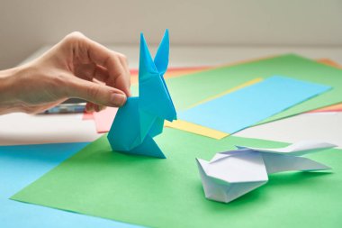 Diy konsepti. Kadın origami paskalya tavşanını renkli kağıttan yapıyor. Origami dersleri