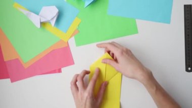 Origami dersleri. Kadın origami paskalya tavşanını renkli kağıttan yapıyor. DIY kavramı