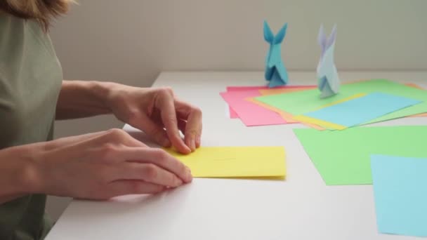 Lecţii Origami. Femeia face origami iepure de Paște din hârtie colorată. Conceptul DIY — Videoclip de stoc