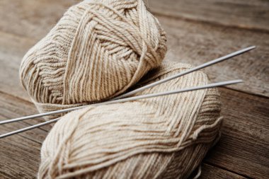 Ahşap arka planda örgü örmek için iki yumak yün iplik ve iğne.