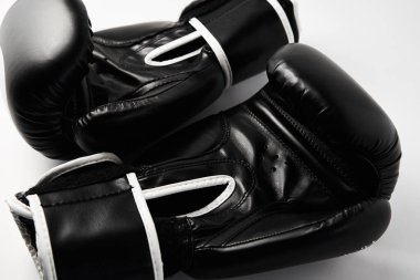 Beyaz arka planda bir çift siyah boks eldiveni, yakın plan.