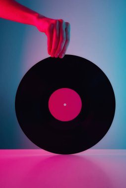 El ele tutuşun, neon ışıklı retro vinil disk. Klasik müzik arkaplanı
