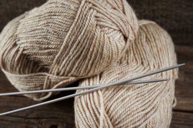 Ahşap arka planda örgü örmek için iki yumak yün iplik ve iğne.