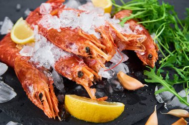 Deniz ürünleri geçmişi. Koyu arkaplanda limonlu taze karides. Kırmızı çiğ karides