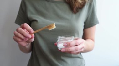 Kadın elinde bambu diş fırçası ve soda tozu tutuyor.