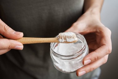 Kadın elinde bambu diş fırçası ve soda tozu tutuyor.