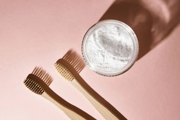Dos cepillos de dientes de bambú y polvo dental sobre fondo rosa — Foto de Stock
