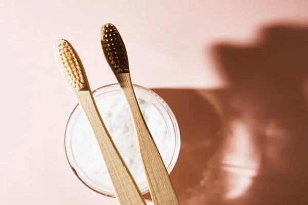 Dos cepillos de dientes de bambú y polvo dental sobre fondo rosa — Foto de Stock