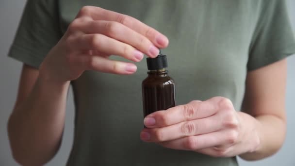 Женщина держит бутылку с косметической сывороткой и эфирным маслом — стоковое видео