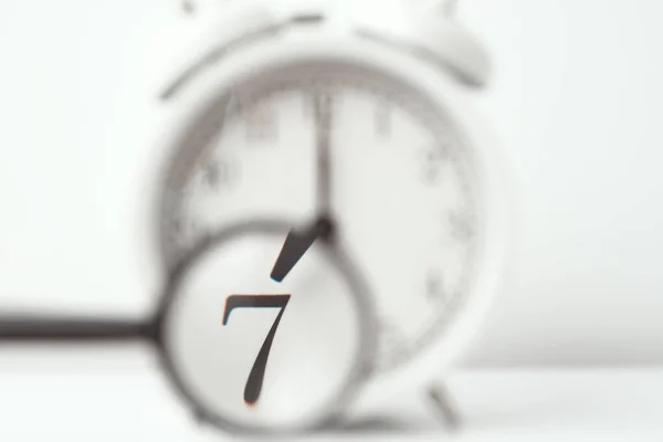 Relógio despertador com acento no número 7 com lupa — Fotografia de Stock