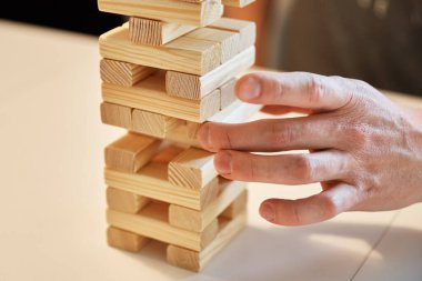 Aile oyunu Jenga. Eller kuleden tahta bloğu alır..
