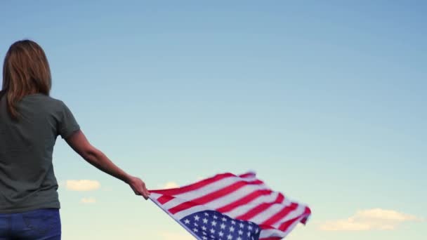 Frau hält US-Flagge gegen blauen Himmel — Stockvideo