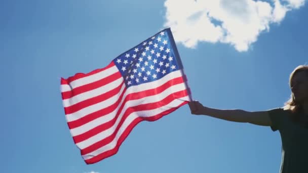 Frau hält US-Flagge gegen blauen Himmel — Stockvideo