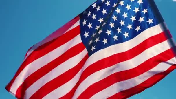 Ondeando bandera de EE.UU. en la mano contra el cielo azul — Vídeo de stock