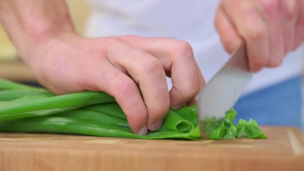 Hombre picando cebolla verde fresca en la tabla de cortar — Vídeo de stock