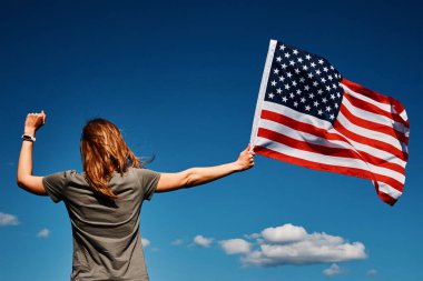 Mavi gökyüzüne karşı bayrağımızı tutan kadın