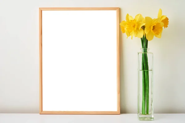 Narciso flores en jarrón y marco vacío sobre fondo blanco — Foto de Stock