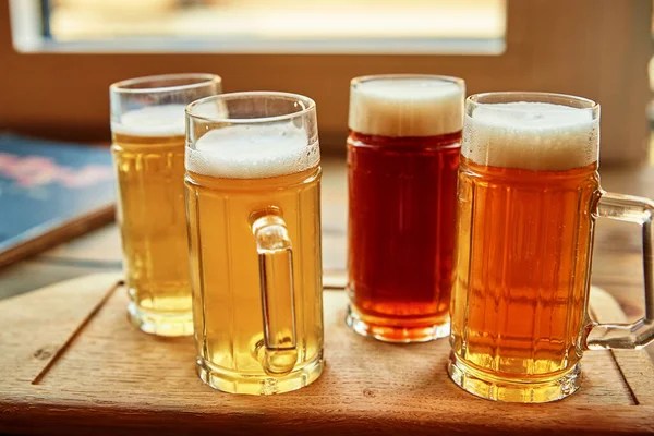 Set of four glasses with different kind of beer on the table — стоковое фото