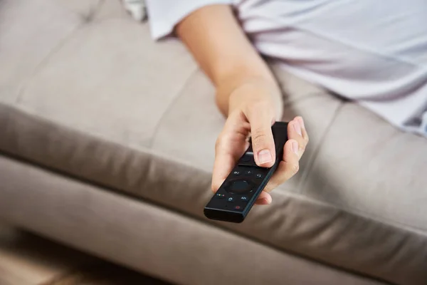 Woman switch channels on TV set with remote control.